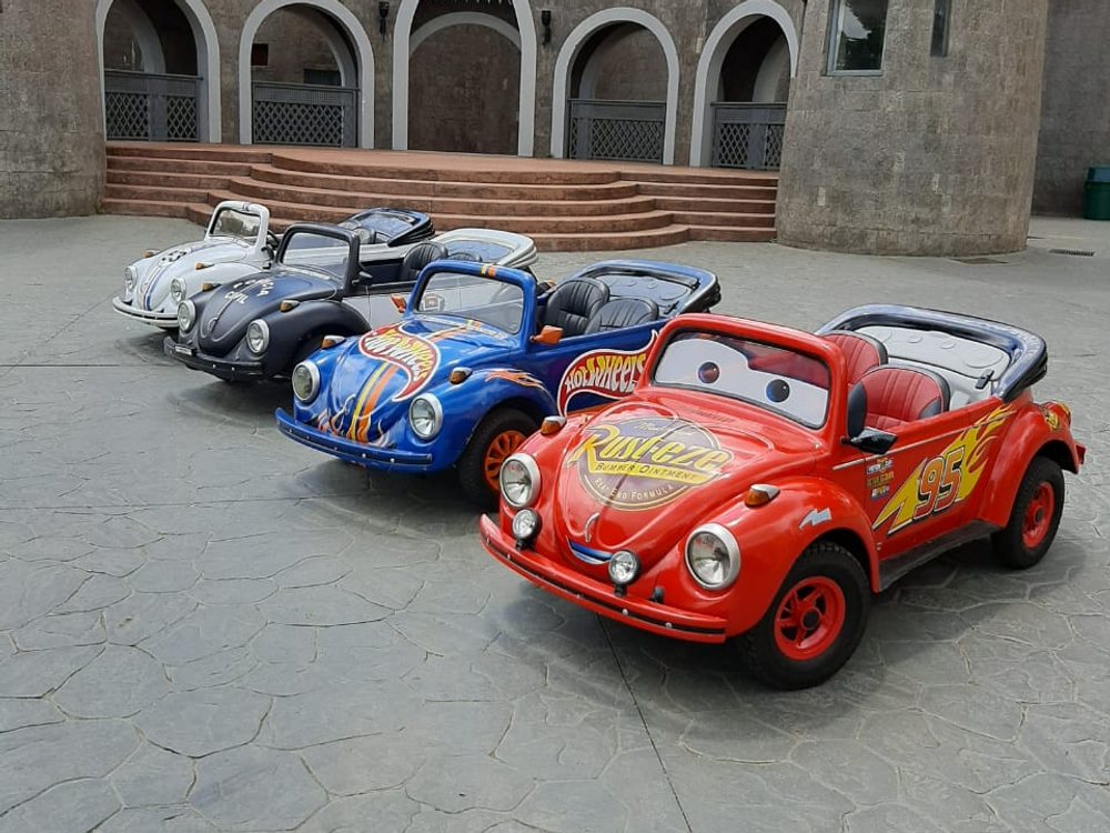 Mini carros fusca personalizados estacionados em frente a um castelo
